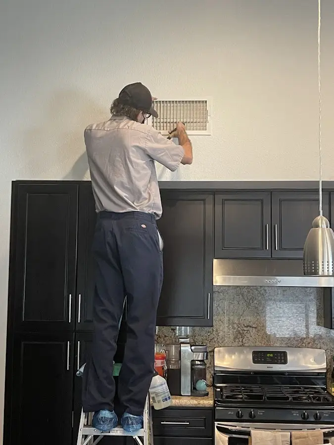 Technician inspecting an air vent during HVAC service in Fairview